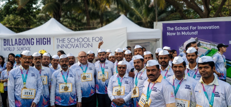 Rows of dabbawalas in white Gandhi caps wearing medals at a school event
